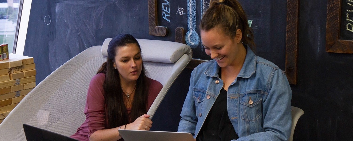 two female marketers laughing as they discuss a project